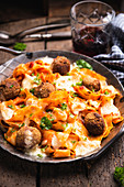 Gratinated tagliatelle with chickpea balls, tomato sauce and almond cheese
