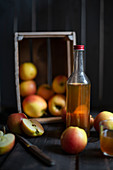 A bottle of cider with a wooden crate of apples in the background
