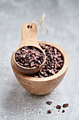 Cocoa nibs in a wooden bowl and a wooden scoop