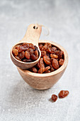 Sultanas in a wooden bowl and a wooden scoop