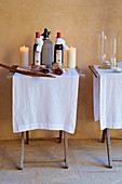 Zwei Klapptische mit weißen Läufern, Weinflaschen und Kerzen