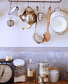 Kitchen utensils hung from rod against wall with patina