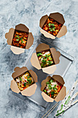 Chilli chicken and oriental noodles with vegetables in take away boxes