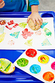Kind macht mit bunten Farben Kartoffeldruck
