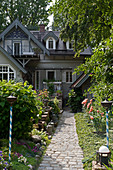 Gepflasterter Weg durch sommerlichen Garten zum Jugendstilhaus