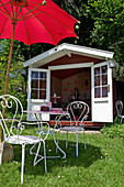 French garden furniture below parasol outside summerhouse