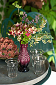 Glasses and vase of flowers on garden table