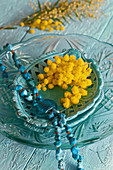 Türkisfarbene Kette und Mimosen auf Keramikschale