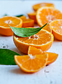 Halbierte Orangen und Orangenschnitze mit Blättern