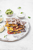 Vegan quesadilla filled with vegan cheese sauce, corn, tomatoes and jalapeno, served with guacamole and soy yogurt
