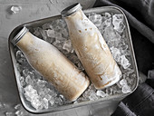 Bottles of ice-cold pea milk on crushed ice