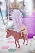 Pink-painted horse with peg, feather and name card