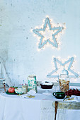 Festive fairy-light stars decorating wall above table set for afternoon coffee
