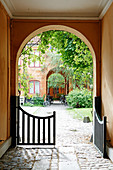 Open gate in arched passageway leading into courtyard