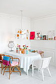 Wicker chairs around table in white dining room with brightly coloured accents
