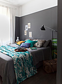 Türkisfarbenes Plaid mit tropischen Motiven auf grauem Doppelbett