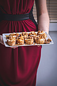 Woman holding a tray with ricotta, honey and walnuts crostini