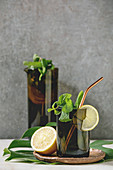 Lemon and mint lemonade in dark glass and jug serving with copper straw