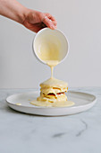 Vanillesauce wird über japanische Souffle-Pancakes gegossen