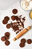 A wooden rolling pin crushing chocolate cookies in preparation for a recipe.