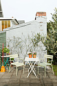 Green garden chairs at folding table on terrace against outside wall of house