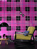 Sessel und Beistelltischchen vor Wand mit großformatigem pink-schwarzem Karomuster
