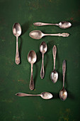 Various vintage teaspoons on a green surface