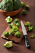 Fresh broccoli with a knife on a wooden chopping board and in a bowl