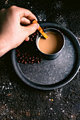 Hand stirring coffee with wooden spoon in metal cup