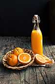 Bottle of fresh citric orange juice placed near halves of fresh oranges