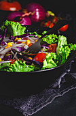 Healthy vegan food with fresh lettuce, cherries tomatoes, red onion and corn on dark background