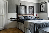 Doppelbett mit recyceltem Holz-Metall-Kopfteil im Schlafzimmer mit grauer Wand