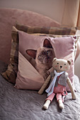Handmade teddy bear and scatter cushion with cat motif on bed