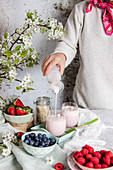 Puring homemade smoothie into glass for healthy breakfast with fresh berries