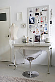 Transparent chair at console table below framed collage