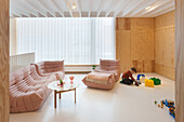 Designer sofa in wood-paneled room with play area for children