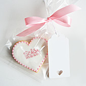 A biscuit with a saying packed in a cellophane bag with a pink bow