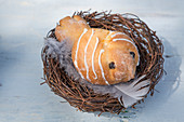 Hen-shaped sweet bun in Easter nest of twigs