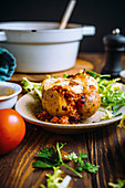 Baked potato filled with spicy bolognese and herb salad
