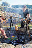Roast chicken hanging in smoke above rustic barbecue pit