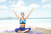 Young woman doing yoga exercise (lotus position) by the sea