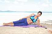 Young woman doing yoga exercise by the sea