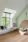 Hanging basket chair with fur next to window seat in bright room
