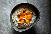 Whole rolled oat Porridge served with persimmon and hazelnuts