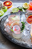 Verschiedene Cocktails auf Tablett mit Eiswürfeln