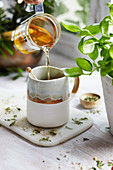 Pouring herbal tea into a tea cup