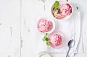 Top view image of pink ice cream balls with raspberries and fresh mint