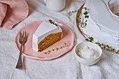 Top view shot of vegan carrot cake with coconut cream frosting with one slice cut and served separately on a plate