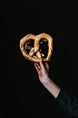 A Hand with a Pretzel on a Black Background