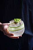 Cocktail with Cucumber in a womans hands